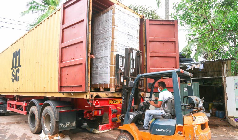 A forklift loading wrapped pallets into a shipping container